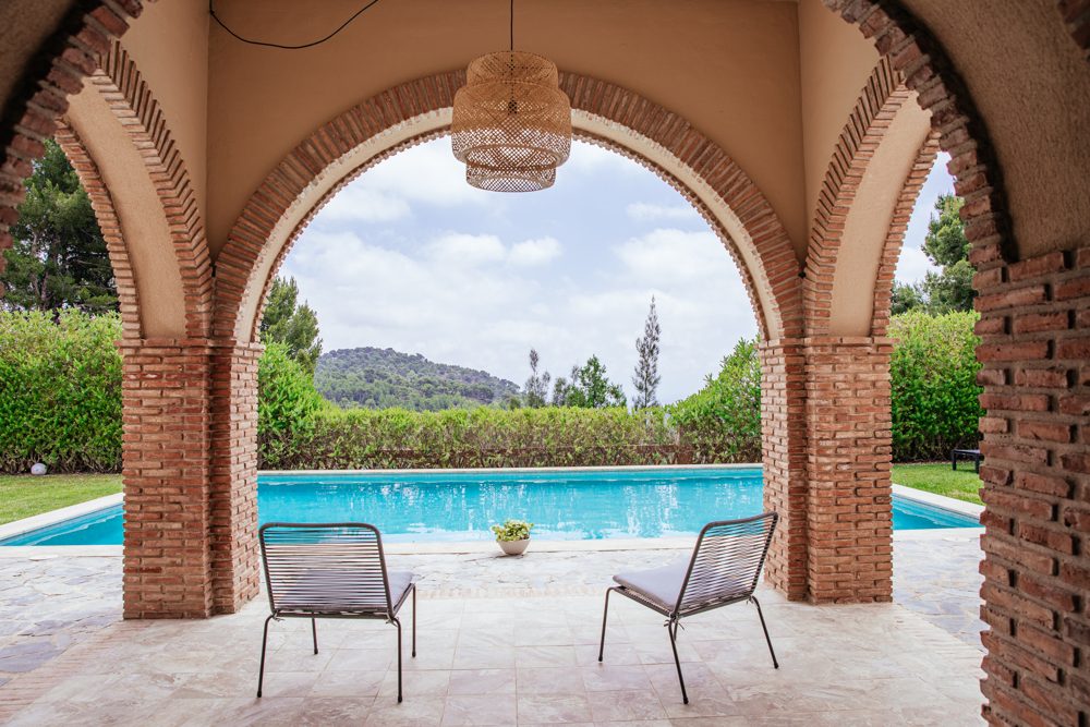 The pool at Savi Coliving, seen through the arched veranda